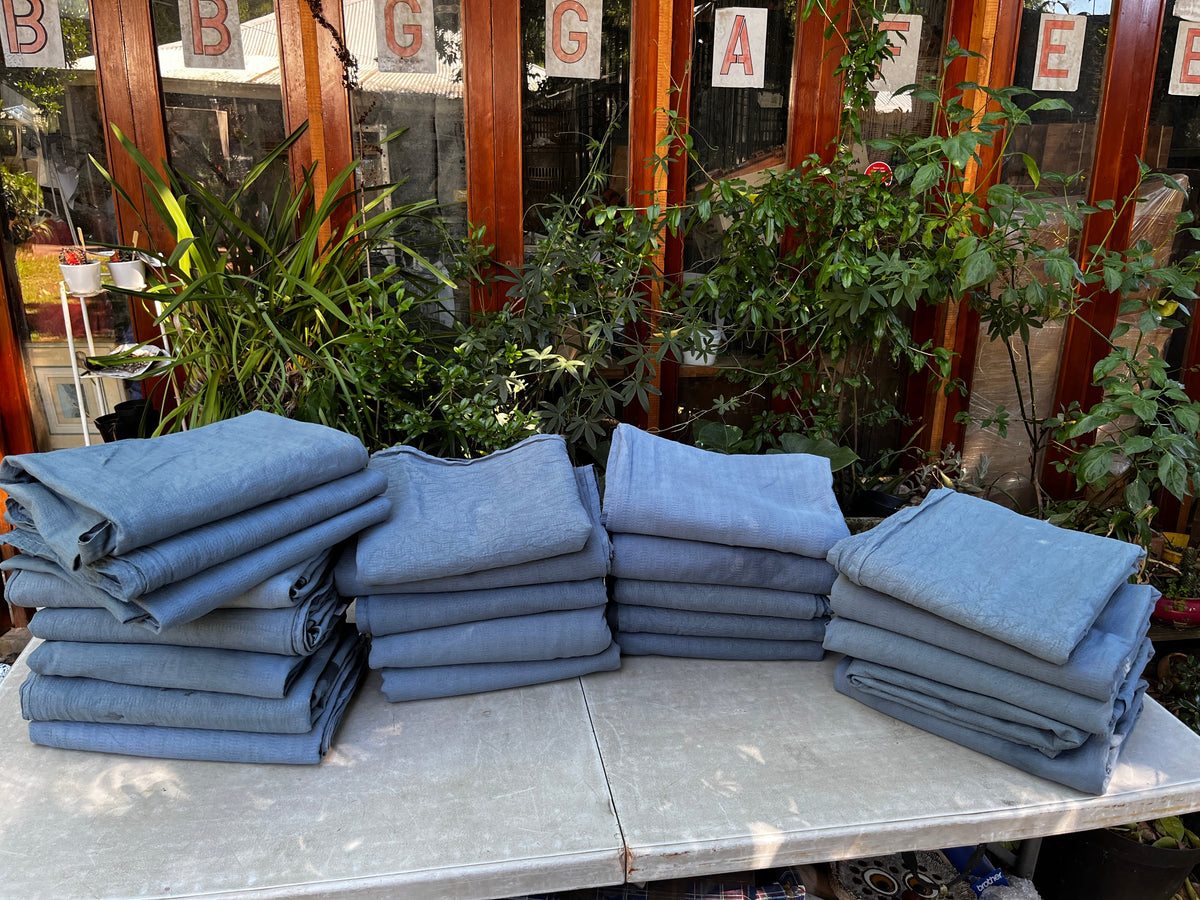 Stacks of folded charcoal-dyed blankets prepared for donation to Wild Heart Wildlife Foundation